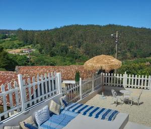 un patio con una valla blanca, una mesa y una sombrilla en Villa Flor Armenteira, en Santa María