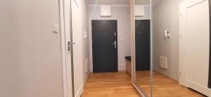 a hallway with a glass door and a mirror at Masurian Apartments in Mrągowo