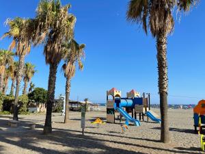 a playground on the beach with palm trees at La Casita del Pescador in Caleta De Velez