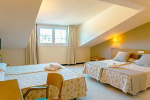 um quarto de hotel com duas camas e uma janela em Hotel Atalaya I em Portonovo