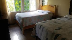 two beds in a room with two windows at Chaudhry House Montego Bays- 2nd floor apt in Montego Bay