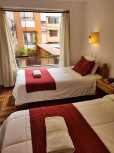 ein Hotelzimmer mit 2 Betten und einem Fenster in der Unterkunft Eco Bunnu Inn in Cusco