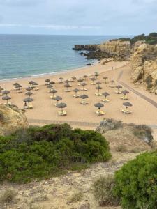a group of umbrellas and chairs on a beach at Parra Home Holidays - Close to Galé Beach in Guia