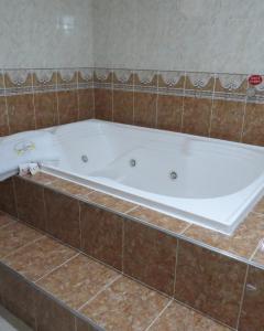 a bath tub in a bathroom with brown tile at Hotel Zulita in Bogotá