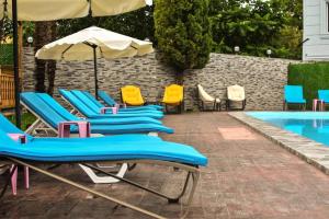 a row of blue chairs and an umbrella next to a pool at Hotel Genatsvale in Batumi