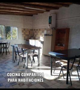 cocina con mesas, sillas y nevera en Amanecer en Cuyo en San Rafael