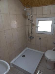 łazienka z prysznicem, toaletą i oknem w obiekcie Hostel Dragana w mieście Podgorica