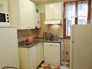 uma cozinha com armários brancos, um lavatório e um frigorífico em Appartamento al Ghetto Vecchio em Veneza