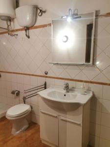 une salle de bain avec un lavabo, des toilettes et un miroir dans l'établissement Appartamento bilocale sulla Via Francigena a Campagnano di Roma, à Campagnano di Roma 7 autres photos