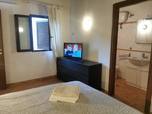 - une chambre avec une télévision sur une commode et un lavabo dans l'établissement Appartamento bilocale sulla Via Francigena a Campagnano di Roma, à Campagnano di Roma
