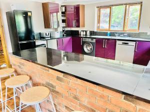 eine Küche mit lila Schränken und einer Ziegelwand in der Unterkunft Grantham House in Grantham
