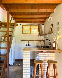 a kitchen with wooden ceilings and a counter with stools at Kanaloa Vibe Stay in Praia do Rosa