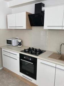 a kitchen with a stove and a microwave at Apartman Duna in Piešťany