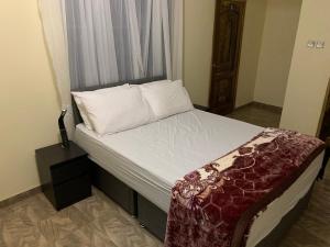 a bed with white sheets and pillows in a room at Top Base Apartments in Accra