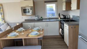 a kitchen with a table with plates and glasses on it at Newquay Bay Resort 181 in Newquay Bay Resort