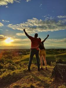Een man en een vrouw op een heuvel met hun armen omhoog. bij Ginebra Glamping in Ginebra