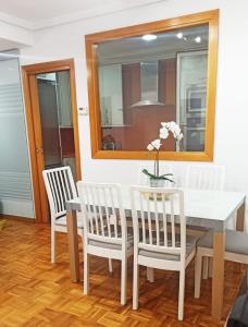 uma sala de jantar com uma mesa, cadeiras e um espelho em Apartamento en San Sebastián con parking em Loyola