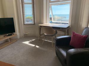 uma sala de estar com um sofá, uma mesa e uma televisão em Beachfront Apartment with BBQ Sun Deck em Bournemouth
