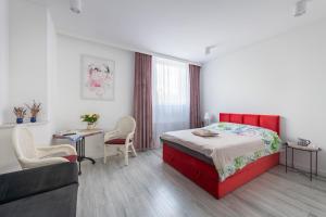 1 dormitorio con cama roja, mesa y sillas en Noclegi Biała Róża, en Bolesławiec