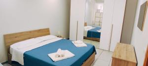 Nino's Apartments في جيارديني ناكسوس: غرفة نوم بسريرين مع مناشف بيضاء ومرآة