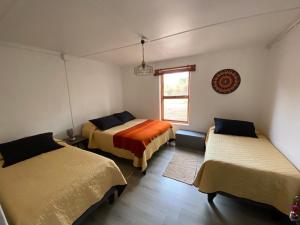 a room with three beds and a window at CaminAndes Hostal in San Pedro de Atacama