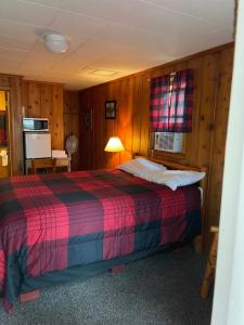 1 dormitorio con 1 cama en una habitación con paredes de madera en FireHouse Inn, en Saint Ignace