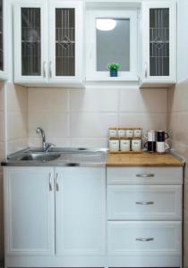 a kitchen with white cabinets and a sink at Apartman Vas dom in Kraljevo