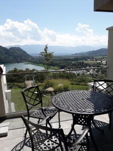 a table and chairs on a balcony with a view of a lake at Apartment Augenweide in Annenheim