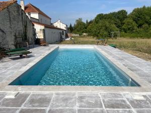 a swimming pool with blue water in a yard at La Maison du Petit Jacques - Mirabelle Cottage in Aumagne