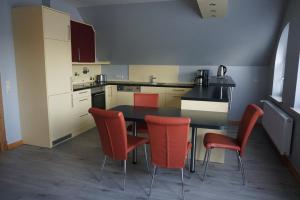 a kitchen with a table and red chairs in it at Villa Ostgardie in Schleswig