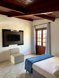 a bedroom with a bed and a flat screen tv at Pousada Souza Reis in São Thomé das Letras