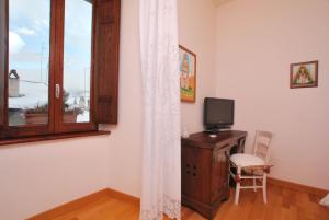 ペスココスタンツォにあるHotel Le Torriのデスク、テレビ、窓が備わる客室です。
