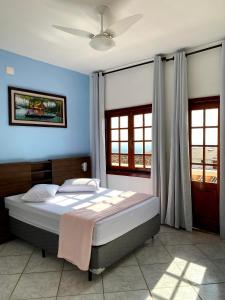 a bedroom with a large bed with blue walls and windows at Pousada Souza Reis in São Thomé das Letras