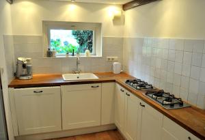 a kitchen with a sink and a stove and a window at 'T Bakhuusje in Putten