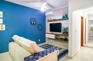 uma sala de estar azul com um sofá e uma televisão em Apartamento Top em Itaguá em Ubatuba
