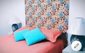 um quarto com uma cama vermelha e 2 almofadas azuis em Apartamento Top em Itaguá em Ubatuba