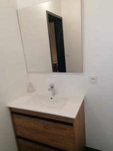 lavabo en el baño con un espejo grande encima. en Chambre privative avec spa en Louplande