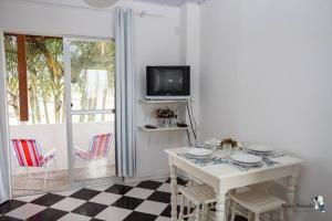 een witte eetkamer met een tafel en een tv bij Residencial di Raffaele em Bombinhas in Bombinhas