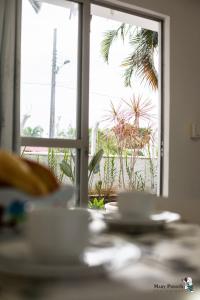 a table with a view of a palm tree outside a window at Residencial di Raffaele em Bombinhas in Bombinhas