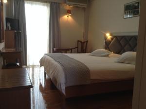 a bedroom with a large bed and a large window at Hotel Nefeli in Volos