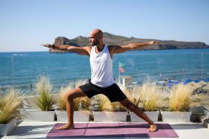 a man doing a yoga pose in front of the beach at Vergina Beach Hotel in Agia Marina Nea Kydonias
