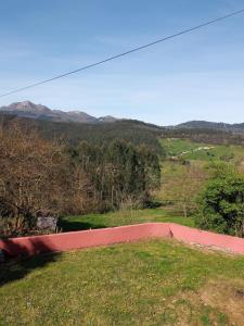 a red wall in a field with mountains in the background at Alojamiento para vocaciónes in Rasines