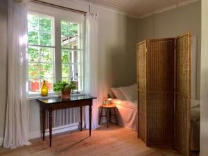 1 dormitorio con mesa, ventana y cama en Borgviks herrgårdsflygel, en Borgvik