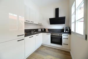 a kitchen with white cabinets and a sink and a tv at Das schiefe Haus Wohnung Bergstraße in Heppenheim an der Bergstrasse +8 photos