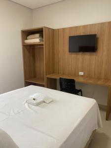 a bedroom with a white bed and a tv on a wall at HOTEL PLAZA PONTES e LACERDA in Pontes e Lacerda