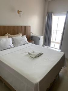 uma grande cama branca com uma toalha branca em HOTEL PLAZA PONTES e LACERDA em Pontes e Lacerda