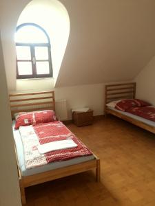 2 camas en una habitación con una ventana abovedada en Penzion Xaver, en Blučina