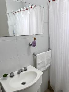 a white bathroom with a sink and a mirror at CHA 413 in Chivilcoy