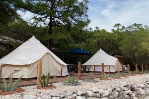two white tents with a table and an umbrella at Glamping San Isidro in Laguna de Sánchez