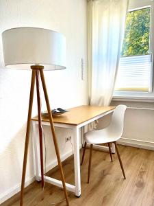 a desk with a lamp and a chair next to a window at Ferienwohnung Kestel ab 2 Nächte in Schopfheim